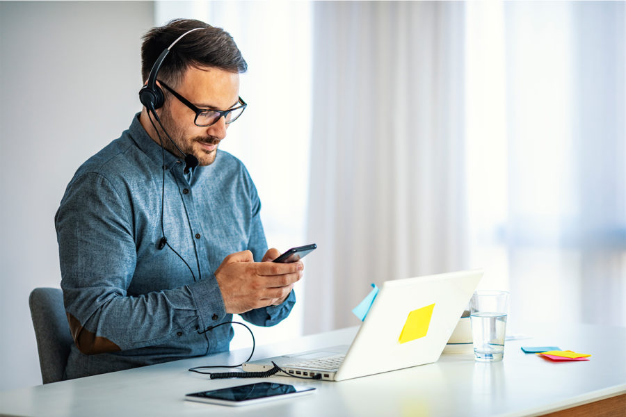 Un joven teletrabaja con sus dispositivos móviles.