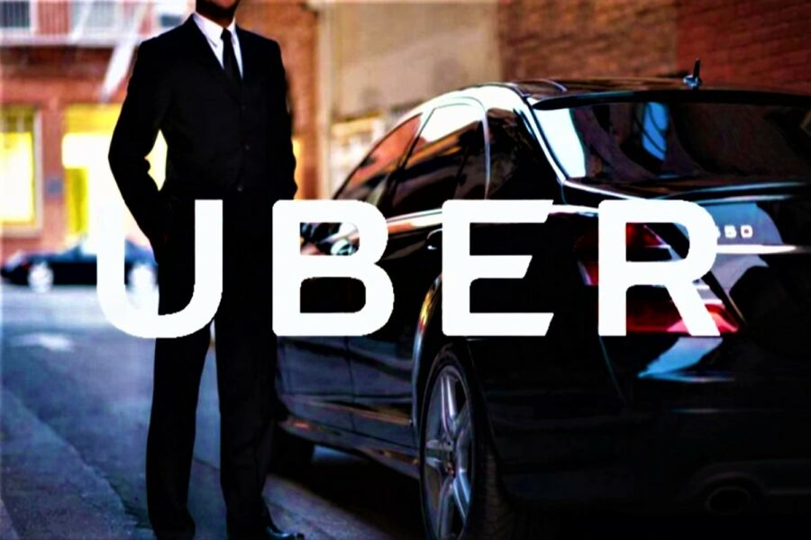 Texto UBER superpuesto a un coche negro y a un conductor de traje y corbata de pie