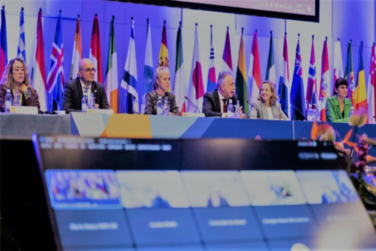 Miembros del gobierno español con banderas europeas al fondo en entorno color azul corporativo de la UE. Fuente imagen: Incibe.