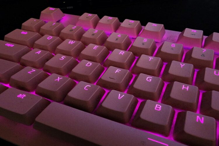 Teclado iluminado entre las teclas con una luz de color fucsia.