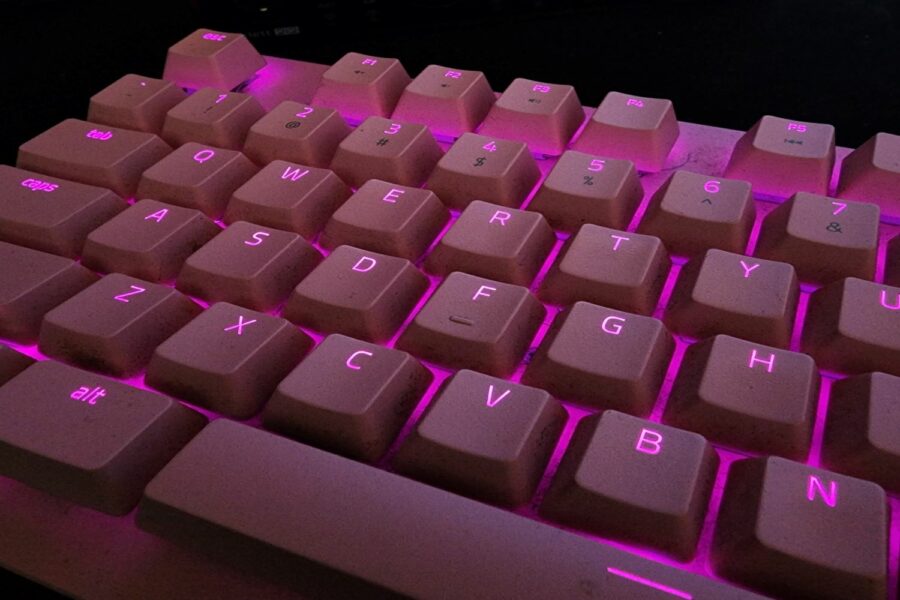 Teclado iluminado entre las teclas con una luz de color fucsia.