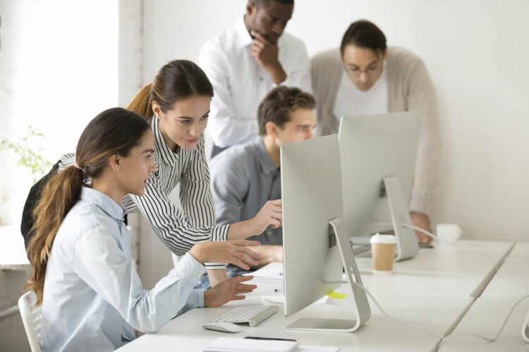 Personas trabajando alrededor de una mesa con ordenadores