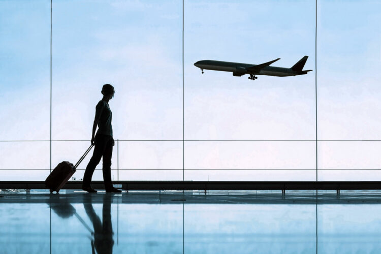 una mujer en un aeropuerto ve despegar un avión a través de una cristalera